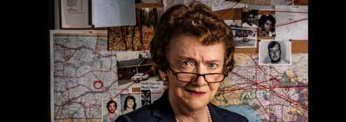 Image - Ann Burgess in front of suspect board; photo by Gary Wayne Gilbert for Boston College magazine; used with permission.