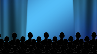 Image - rear view of audience members looking at stage curtains