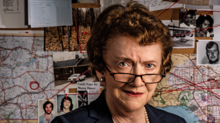 Image - Ann Burgess in front of suspect board; photo by Gary Wayne Gilbert for Boston College magazine; used with permission.